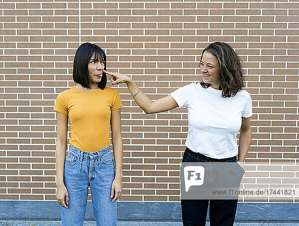 Playful lesbian couple in front of brick wall