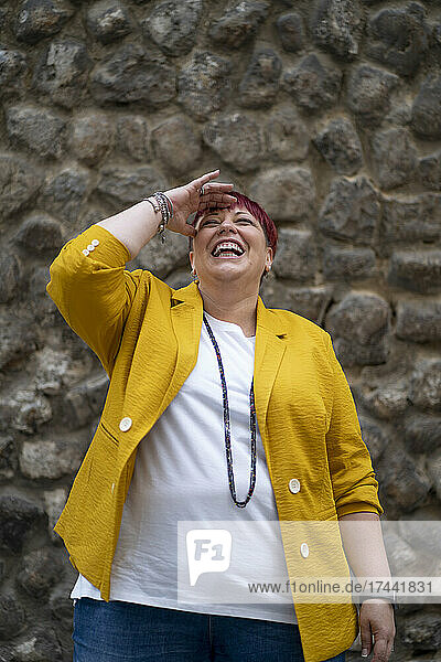 Mature woman laughing while standing in front of wall