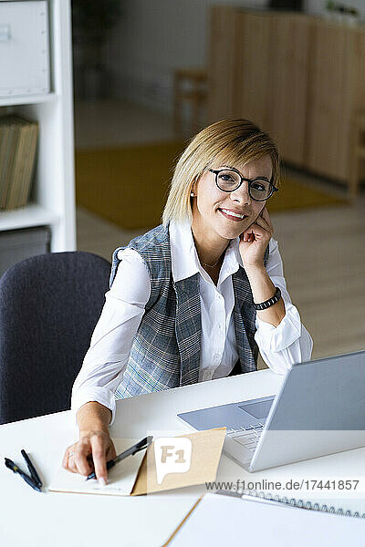 Mittlere erwachsene Geschäftsfrau sitzt am Schreibtisch im Büro