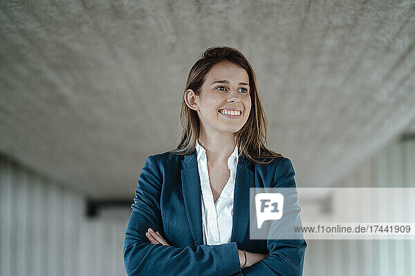 Businesswoman with brown hair standing with arms crossed