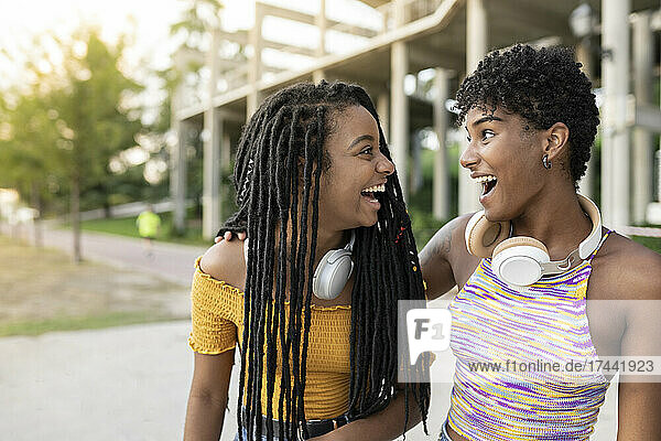Cheerful young women laughing while looking at each other