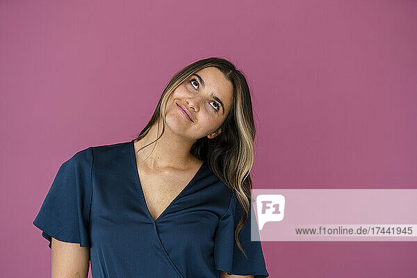 Thoughtful businesswoman in front of pink color wall
