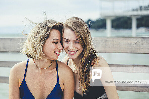 Smiling mother and daughter wearing cocktail dress in front of railing