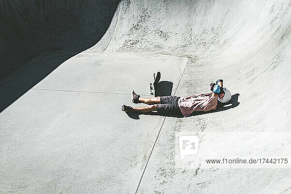 Male athlete relaxing at skateboard park on sunny day