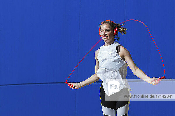 Sportlerin springt Seil vor blauer Wand