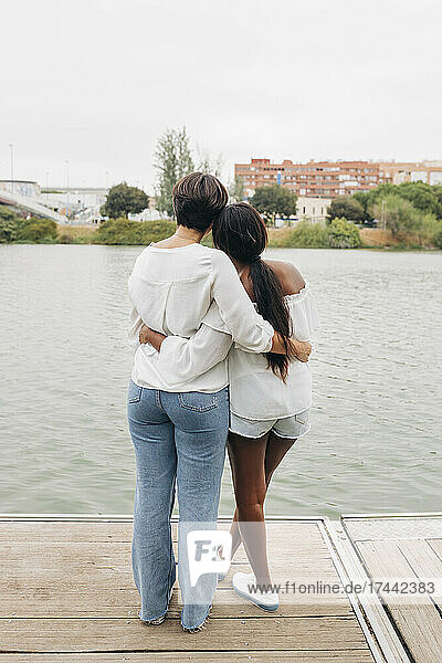 Lesbisches Paar mit Armen und Blick auf den See