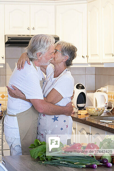 Älteres Paar umarmt sich zu Hause in der Küche