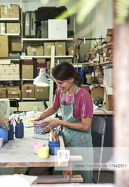 Smiling female store owner arranging concrete designs while working in workshop