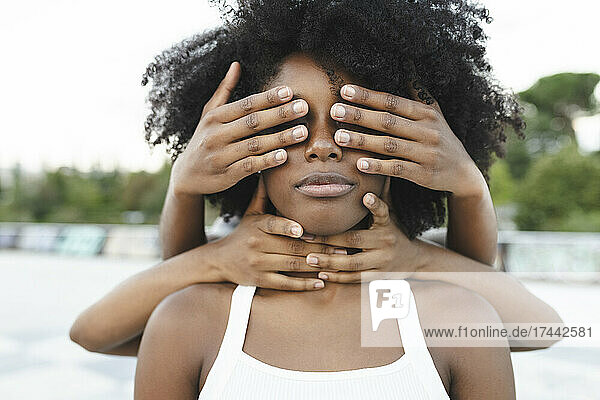 Female friends covering eyes of Afro woman