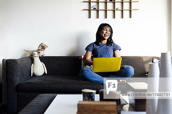 Happy woman with laptop on sofa at home