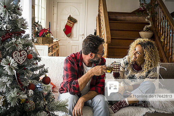 Happy couple toasting with coffee at home during Christmas