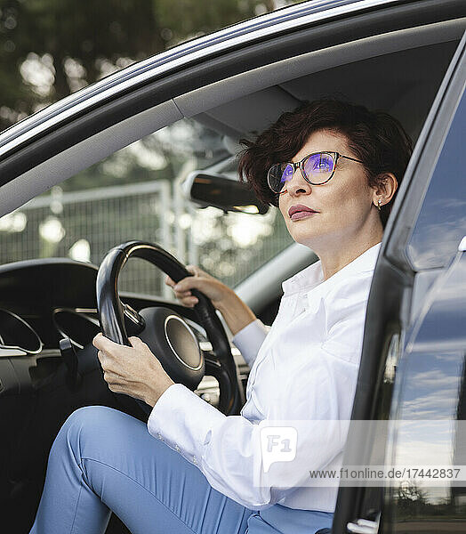 Berufstätige Frau hält Lenkrad  während sie im Auto sitzt