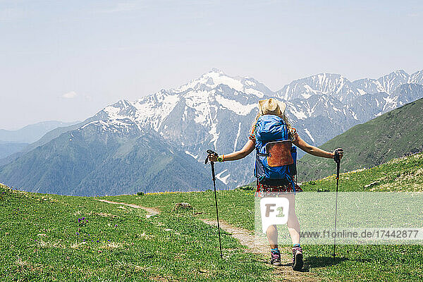 Female backpacker hiking on mountain during sunny day