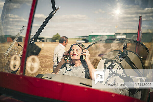 Smiling woman wearing headphones in propeller airplane