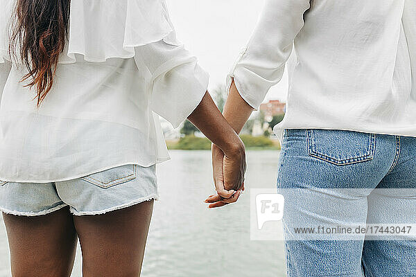 Girlfriends holding hands at lakeshore