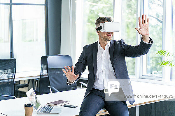 Businessman gesturing while wearing virtual reality headset in office
