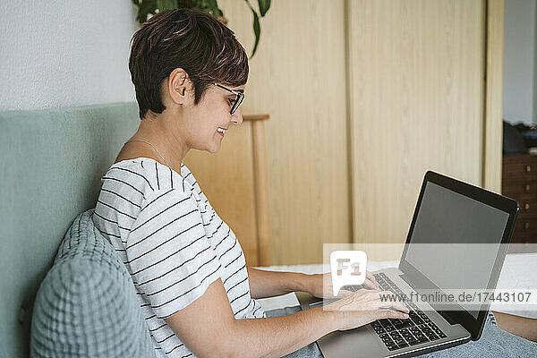 Mid adult woman using laptop while sitting in bedroom