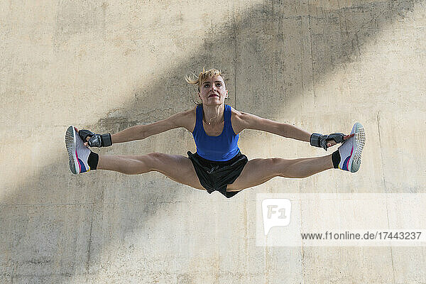 Sportswoman doing splits in front of wall