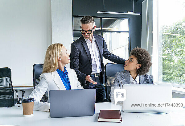 Businessman discussing with female colleagues in office