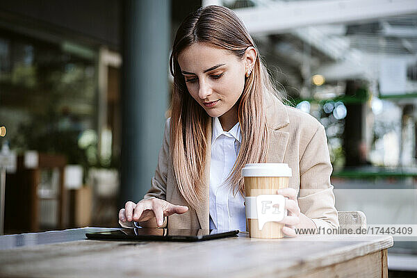 Female business professional using digital tablet at cafe table
