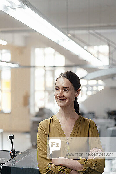 Smiling female professional with arms crossed in industry