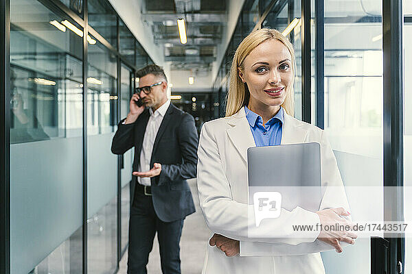 Businesswoman with male colleague standing in corridor at office