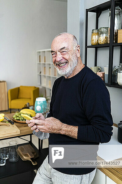 Happy man holding smart phone in kitchen