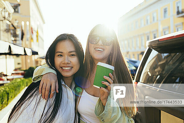 Smiling female friends with long hair during sunny day