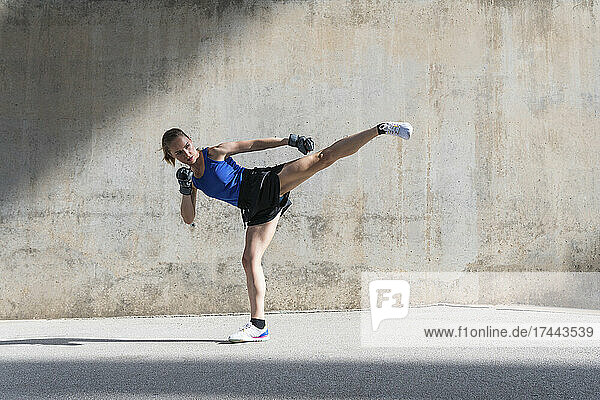 Female athlete practicing kicks in front of wall