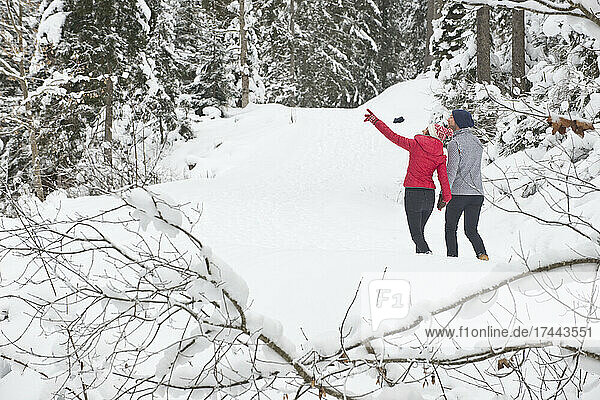 Frau gestikuliert beim Spaziergang mit Mann im Schnee
