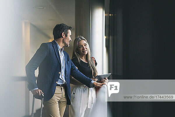 Smiling businesswoman and male professional talking in hotel
