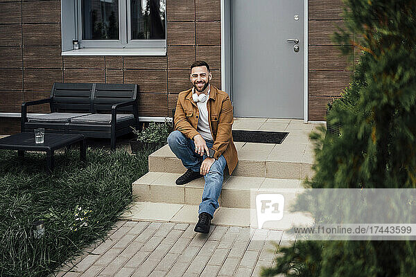 Smiling mid adult man sitting on steps at backyard