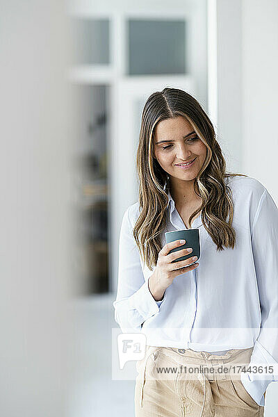 Female business professional holding coffee cup in office