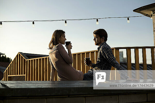 Couple talking while having drink on rooftop