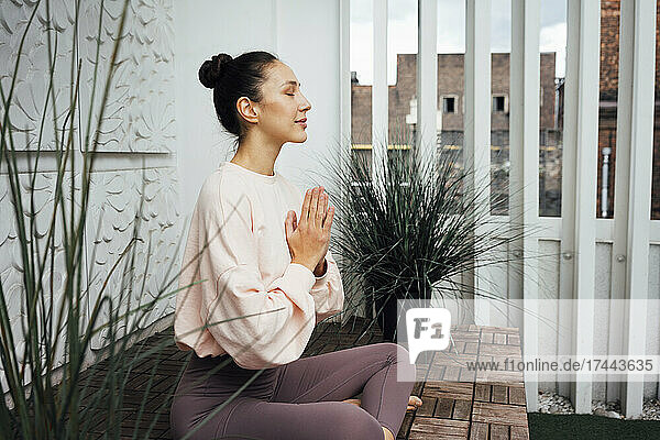 Woman with hands clasped practicing yoga on terrace