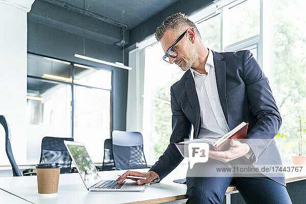 Mature businessman working on laptop in office