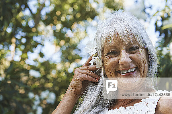 Smiling senior woman wearing flowers in hair at park