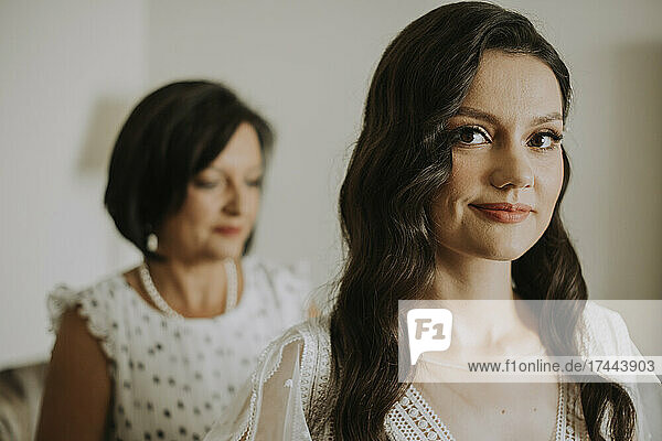 Smiling bride with mother at home