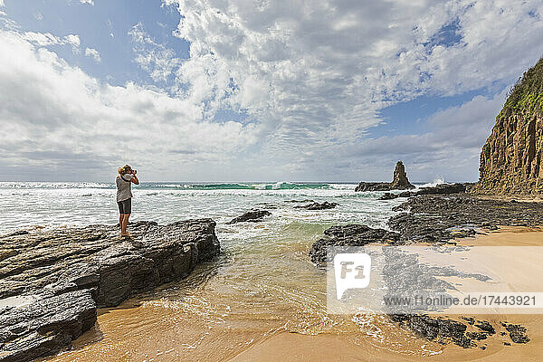 Female tourist photographing Cathedral Rocks at Jones Beach  Australia