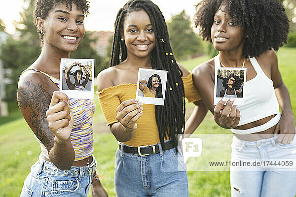 Smiling young women showing photographs at park