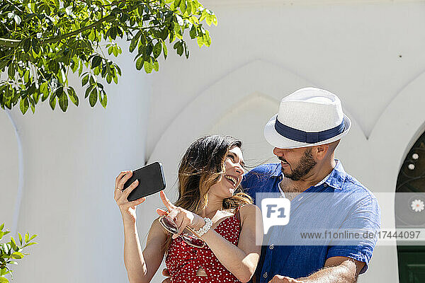 Happy woman showing mobile phone to man during sunny day