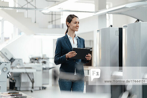 Female business professional holding digital tablet in industry