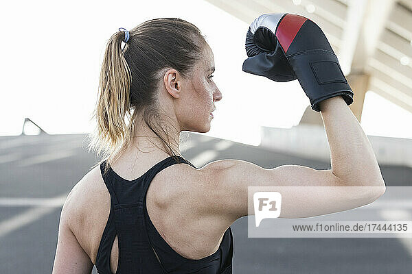 Female athlete wearing boxing glove flexing muscles