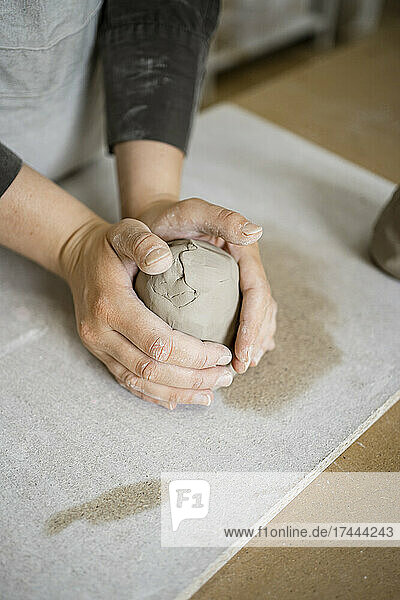 Female craft expert molding clay on workbench