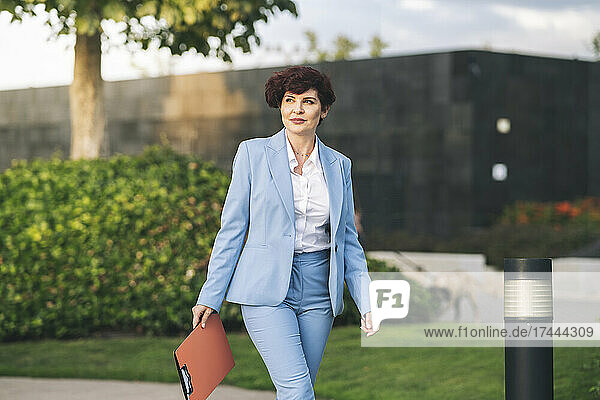 Mature female professional with file walking at office park