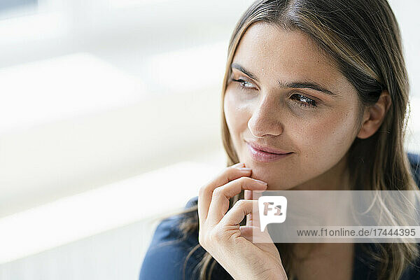 Thoughtful young female professional with hand on chin