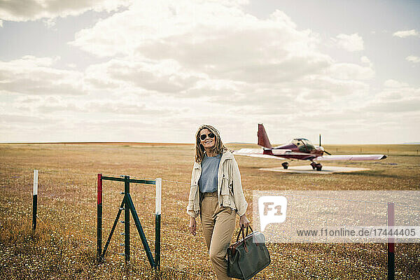Lächelnde Frau mit Tasche auf dem Flugplatz