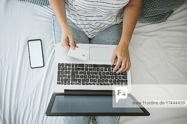 Woman doing home shopping on laptop while paying through credit card at home