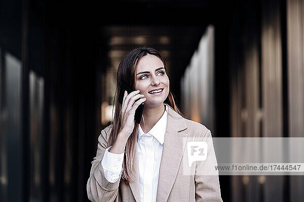 Businesswoman talking on mobile phone at corridor