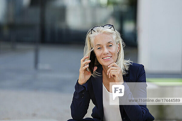 Businesswoman with hand on chin talking on smart phone